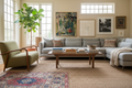 A living room assembled over a lifetime — vintage rug, midcentury chair, art leaned against the wall, handmade ceramic bowl — personal, not decorated
