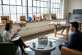 A Studio Collective principal and client in conversation at the Venice studio — sketchbook in hand, project photos on a tablet, two cups of coffee between them